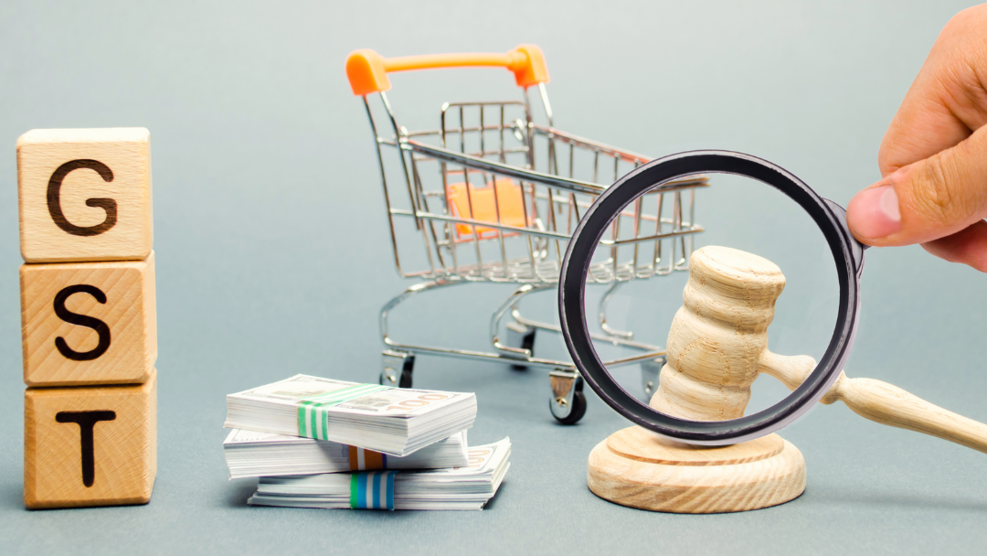 WOODEN blocks with word GST, money and a super marke trolley with a judge's gavel